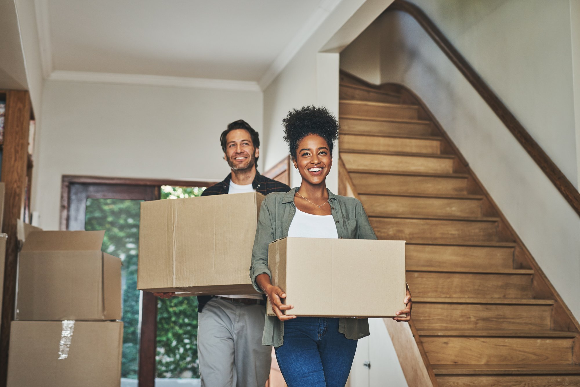 Happy couple moving into their first home holding cardboard boxes Happy couple moving into their first home holding cardboard boxes