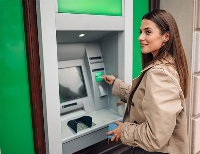 Smiling woman visiting green backlit ATM