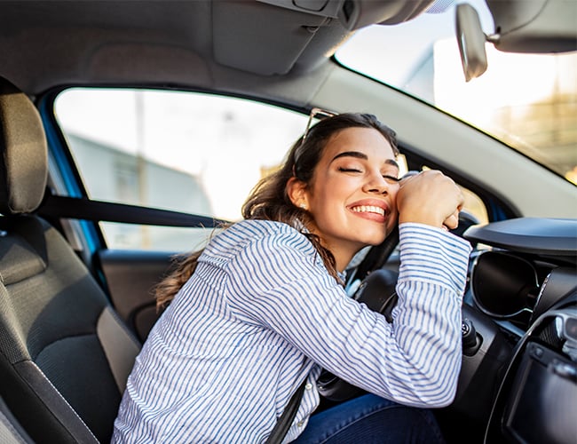 Young brunette woman hugging steering wheel in car Young brunette woman hugging steering wheel in car