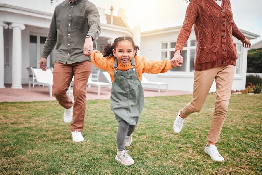 Child running between parents outside their family home.