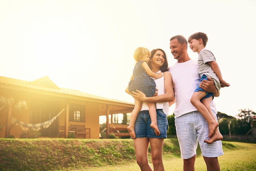 Parents holding their children while standing outside near their family home. Parents holding their children while standing outside near their family home.