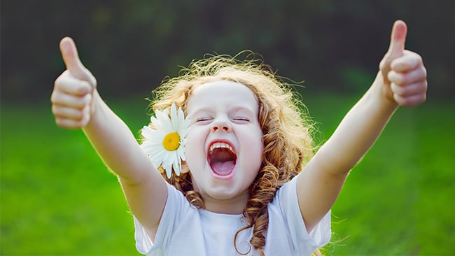 Little girl with flower in her hair giving two thumbs up